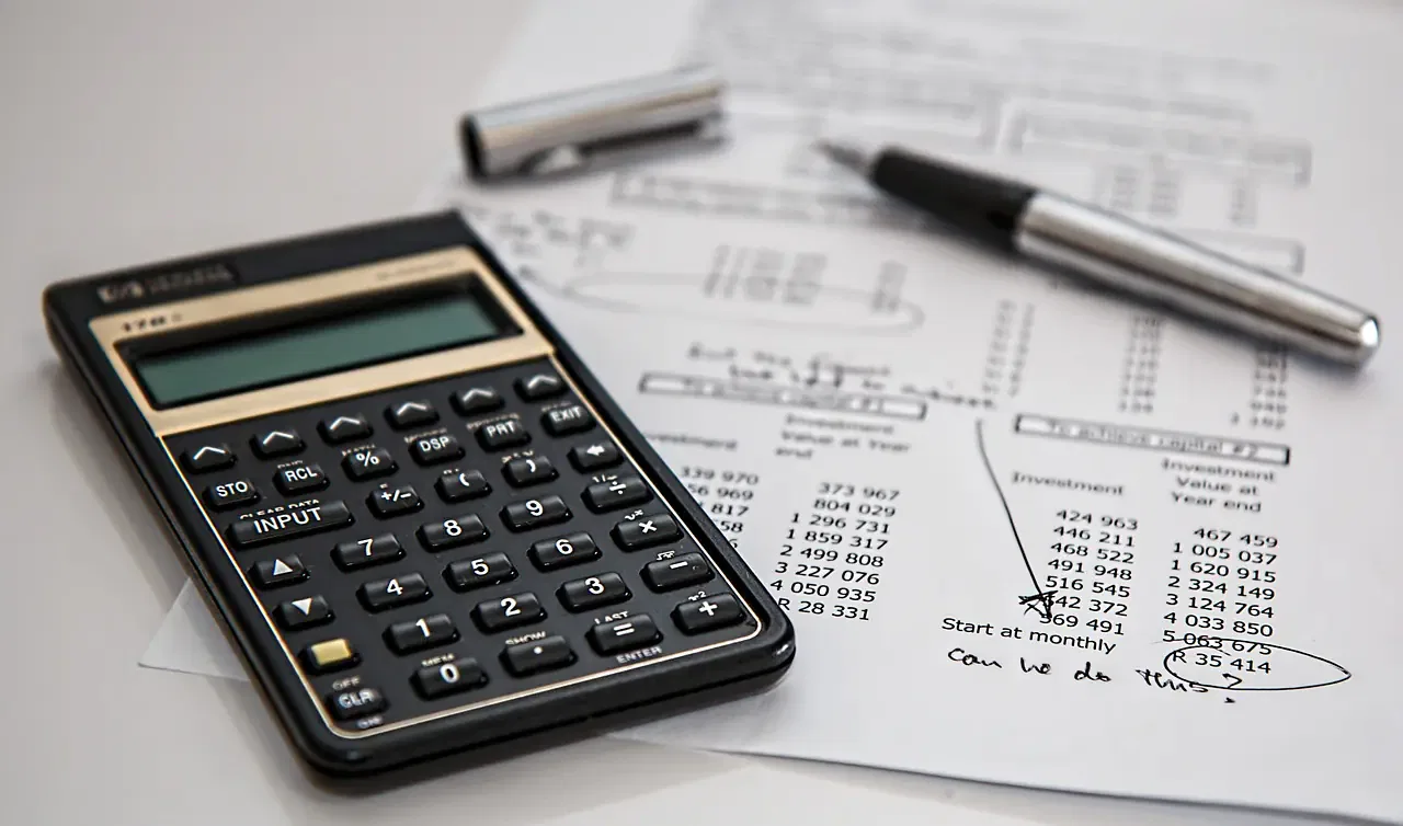 A calculator and pen on a financial document with handwritten notes and circled figures.