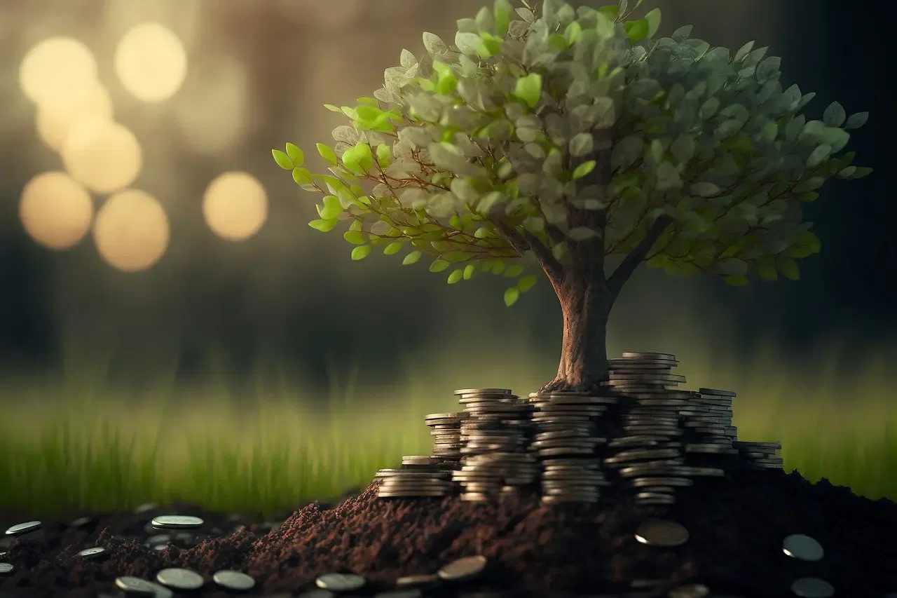 A small tree grows from a mound of soil and coins, symbolizing financial growth and investment in a natural setting.
