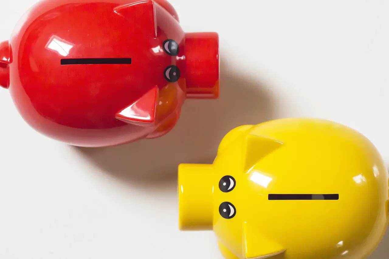 Red and yellow piggy banks on a white background, viewed from above.