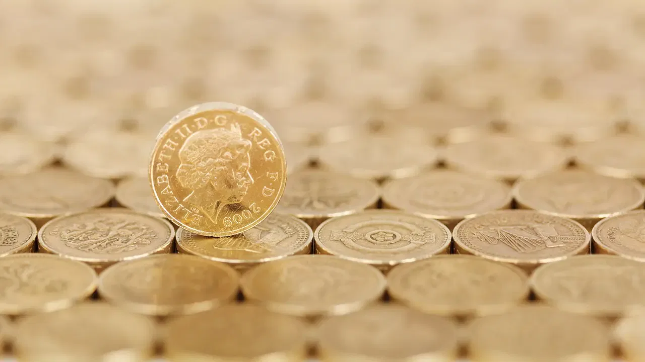 Close-up of a single standing one-pound coin among many others laid flat, showing the year 2009 and a profile of a person's face.