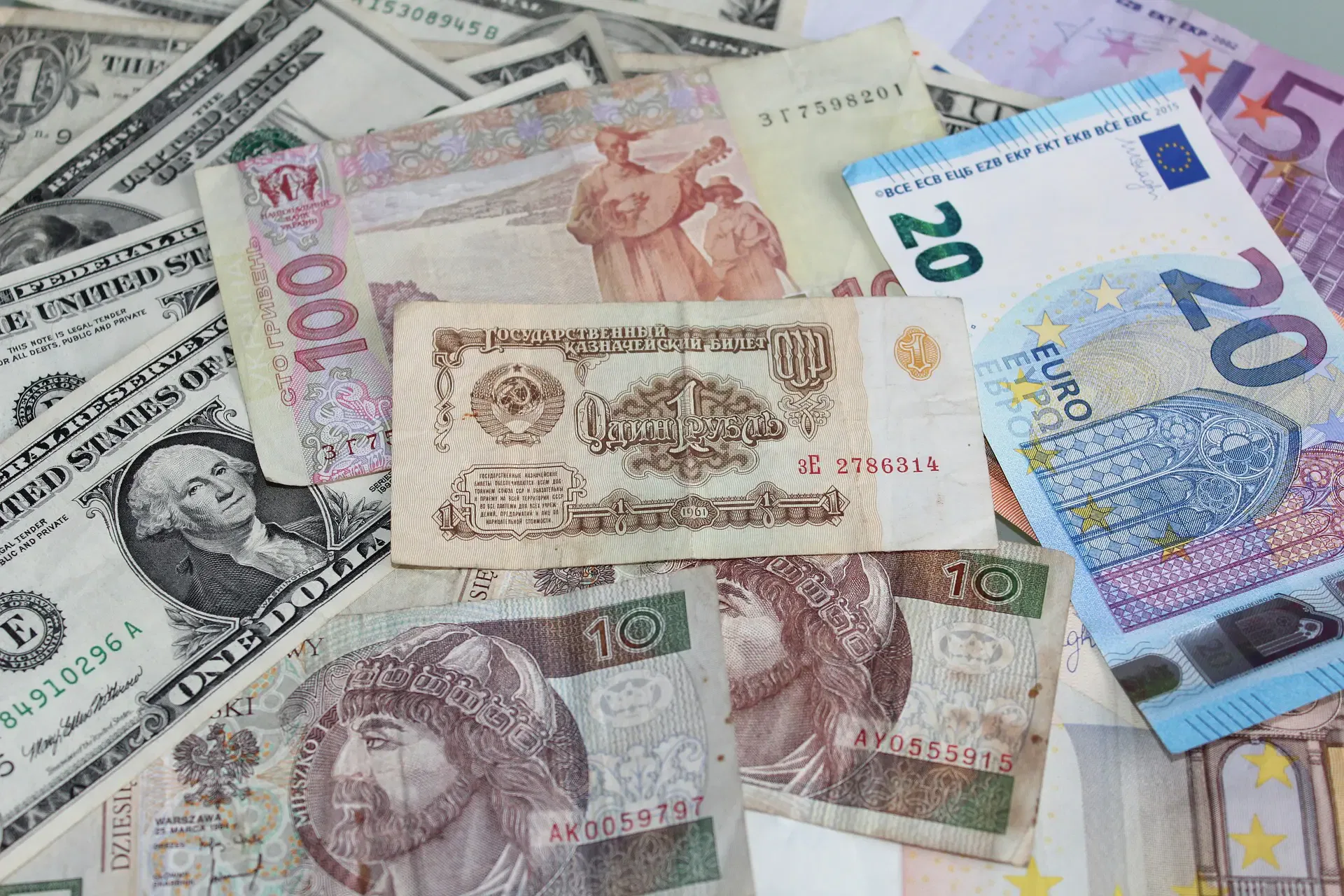 Various international currencies including US dollars, euros, and other global banknotes scattered on a surface.