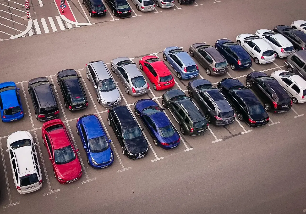 Aerial view of a parking lot filled with various colored cars arranged neatly in rows.