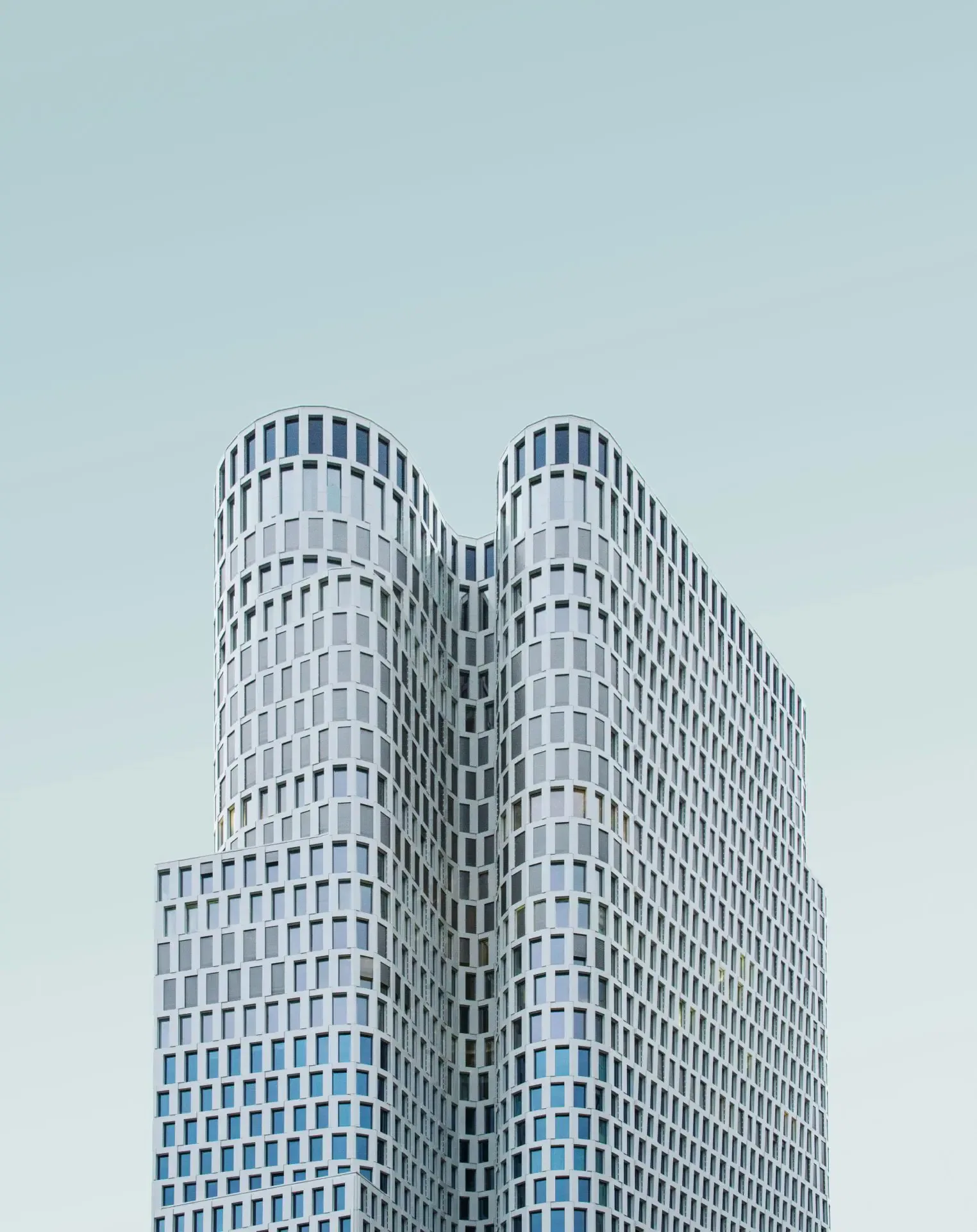 Modern high-rise building with a unique wavy architectural design against a clear sky.