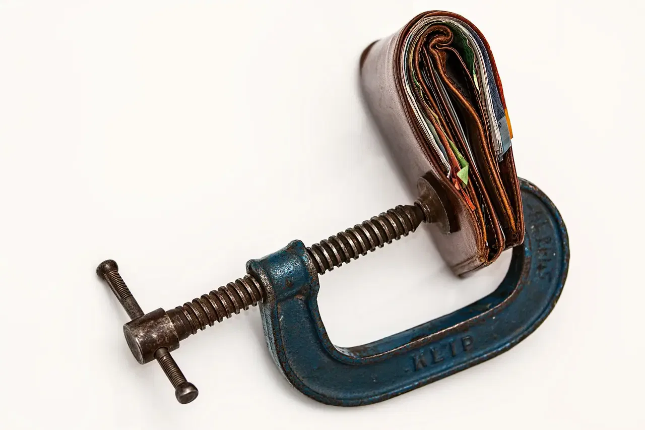 Wallet clamped in a vise, illustrating financial pressure and the importance of international estate tax planning.