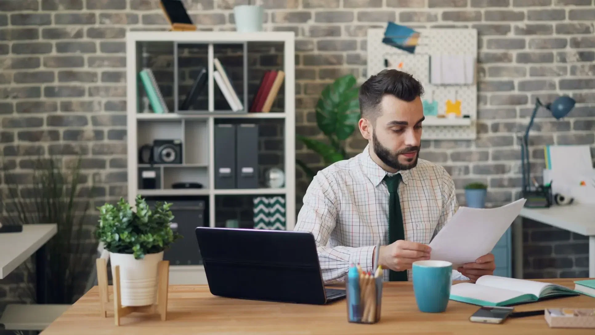 Man in office reviews documents on how to determine tax residency, with a laptop and coffee mug on the desk.