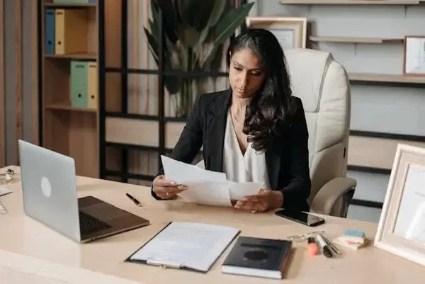 Person reviewing defamation documents related to owners corporation at a desk, with laptop and files nearby.
