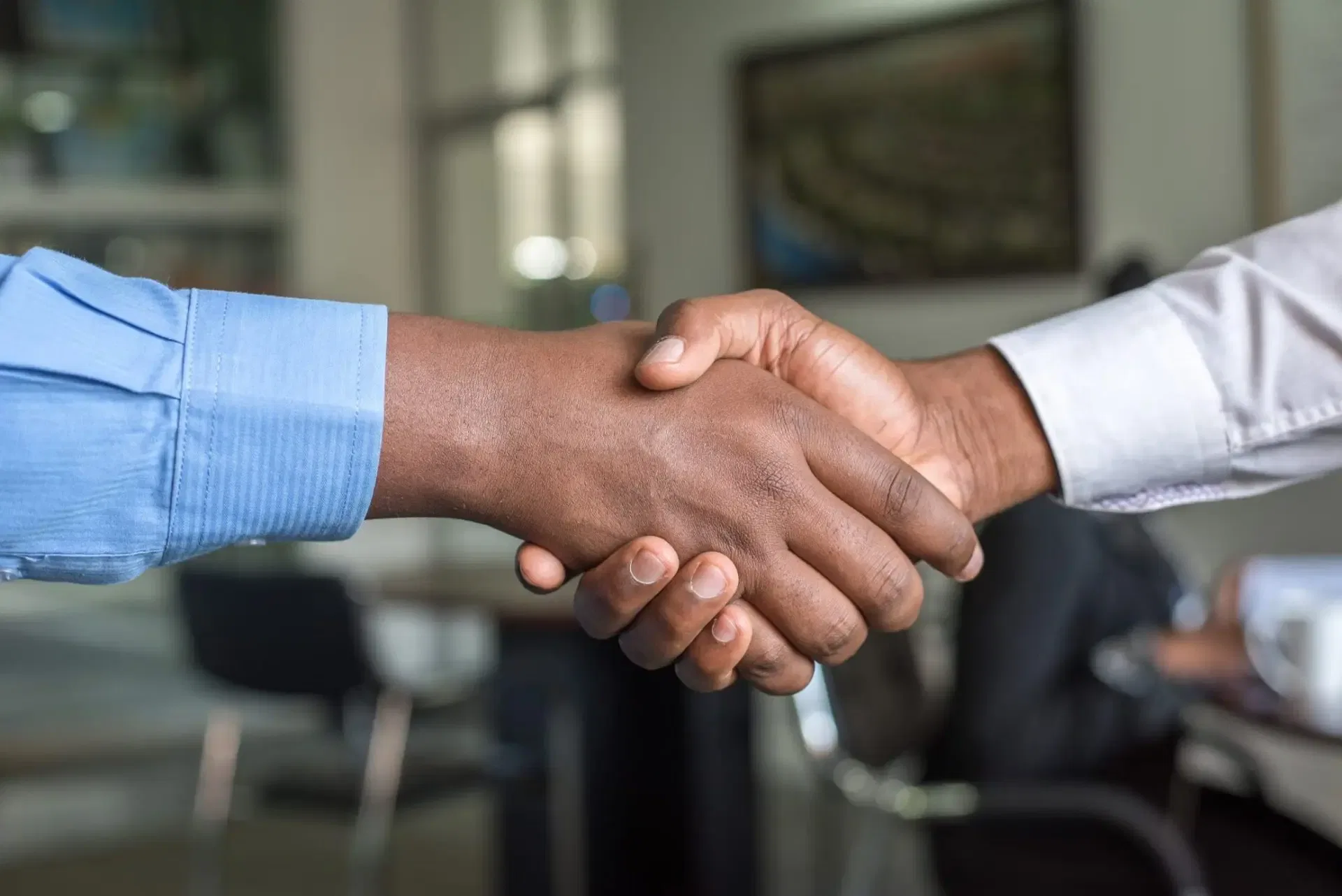 Two people shaking hands in an office, symbolizing partnerships in international estate planning.