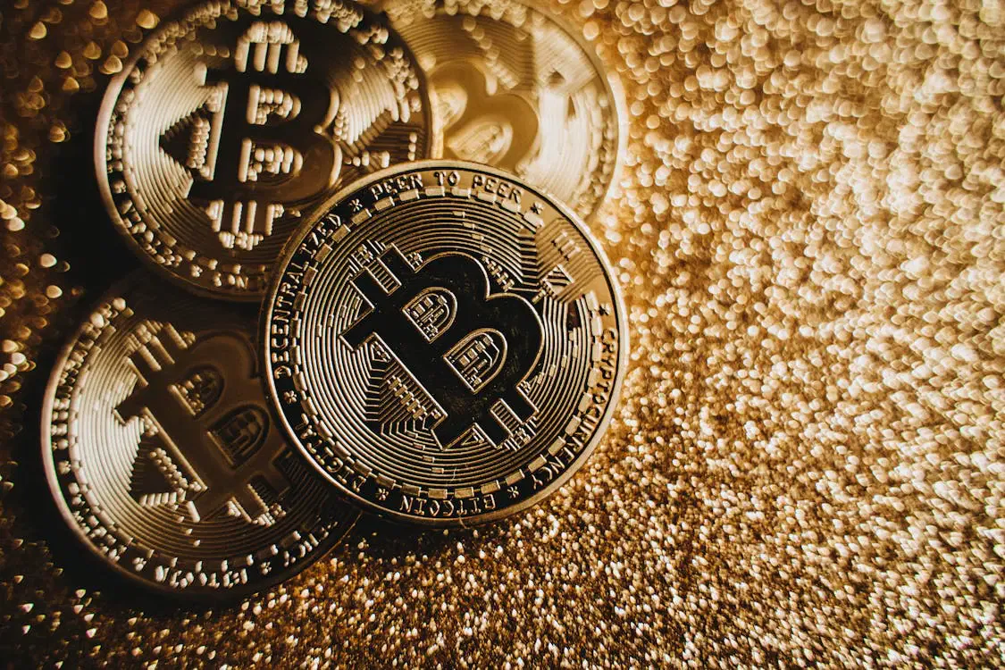 Bitcoin coins on a glittering surface, representing digital assets in international estate planning.