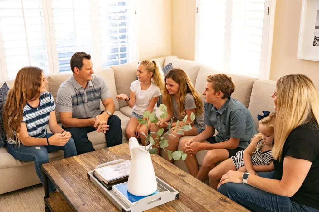 Family discussing rules for family councils, seated on a sofa around a wooden table in a cozy living room.