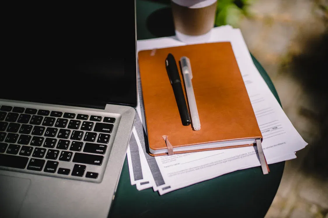 Laptop and notebook on table with documents, symbolizing international estate planning for digital nomads and mobile lifestyles.