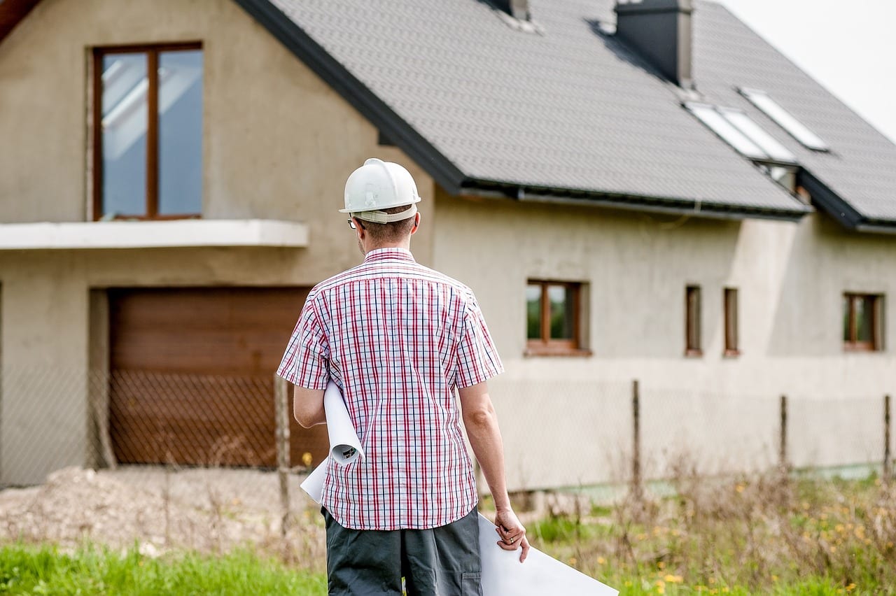 Man in hard hat examines building plans, illustrating NSW Building Defect Claims and 6-Year vs 2-Year Warranty Limits.