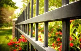 Close-up of a metal fence with greenery, illustrating the topic of who pays for dividing fence repairs in strata.
