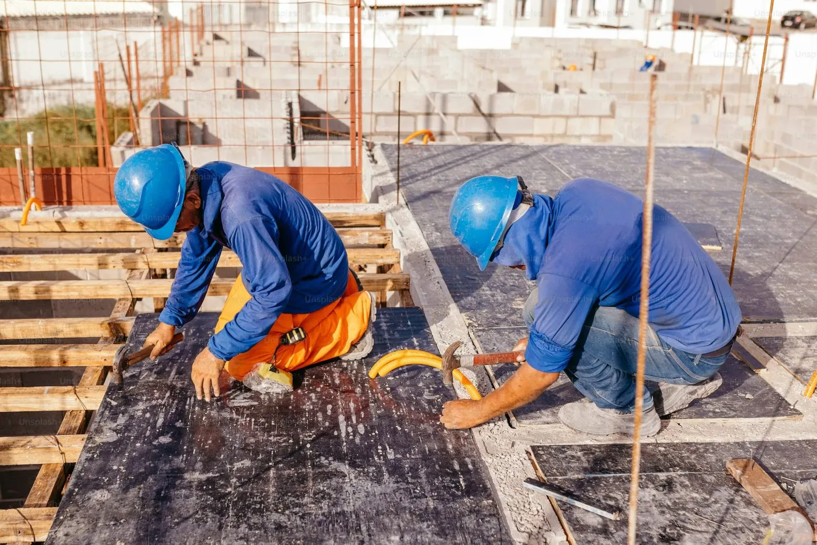 Workers wearing blue helmets and shirts perform unapproved building works on a construction site in NSW.