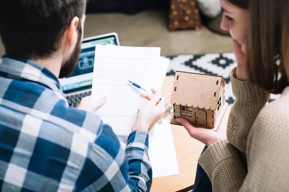 Couple reviewing NSW strata documents, holding a model house.