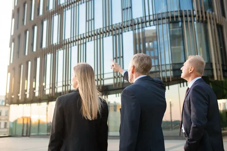 Three business professionals discuss international estate planning in Sweden, reviewing a building.