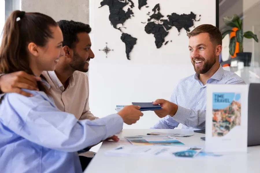 Travel agent handing passports to happy couple planning overseas trip.