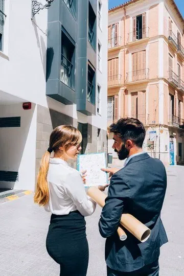 Two real estate agents reviewing property plans in Malta.
