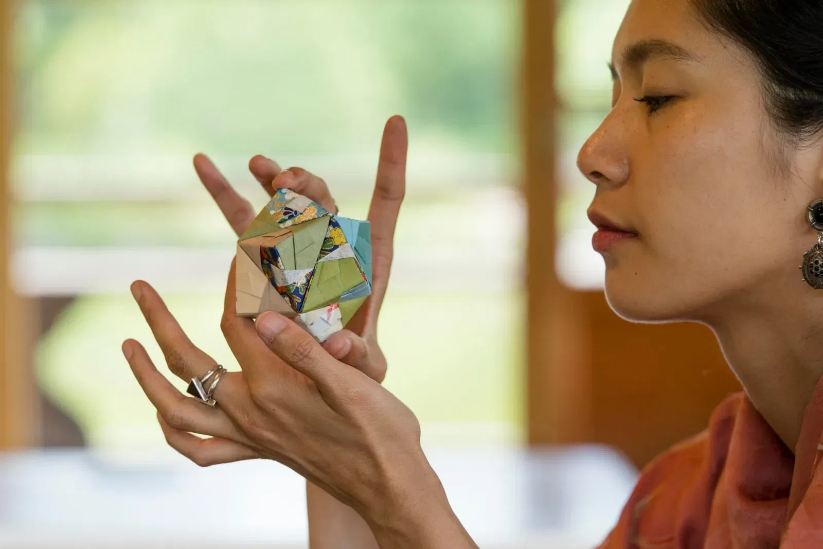 Woman's hands carefully holding a colorful origami creation.