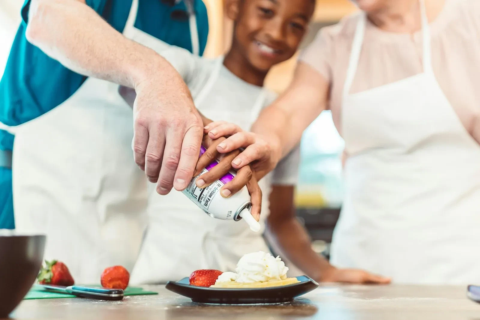 Grandparents and grandchild decorate a dessert together.