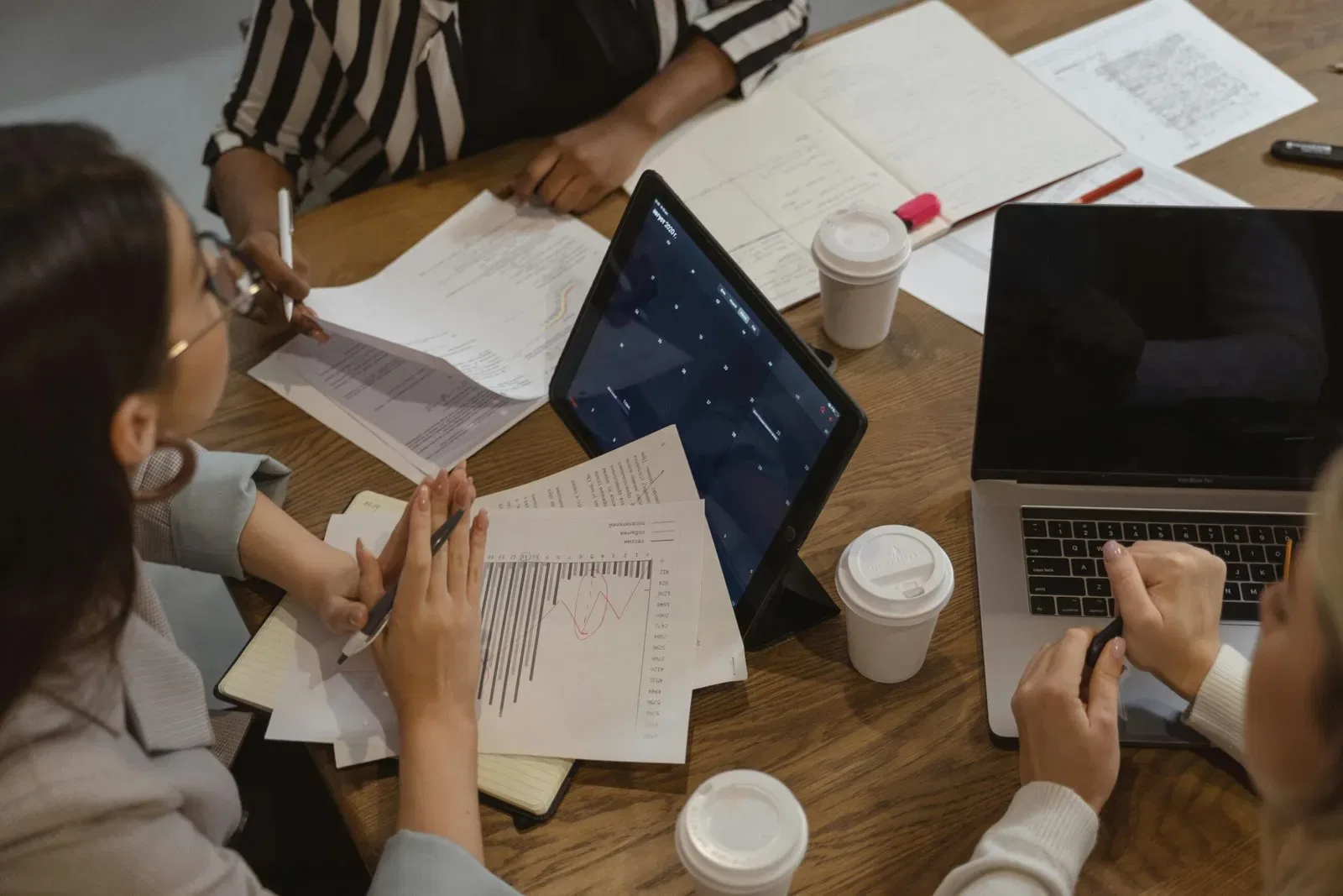 Businesswomen reviewing documents and graphs during a meeting.