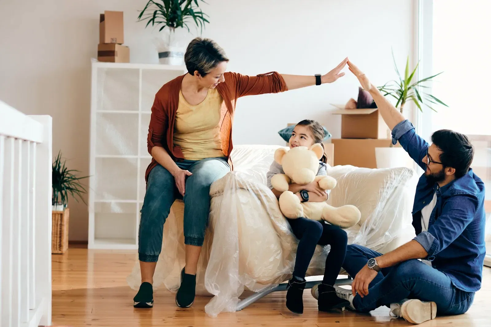 Family sitting together in a living room, child holding a teddy bear