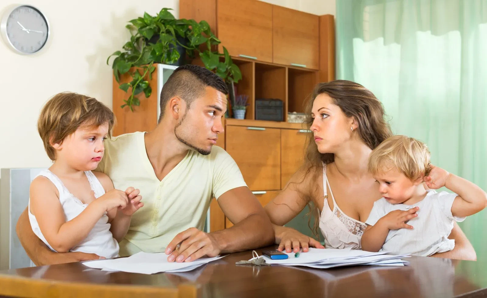 Serious couple with children discussing documents at table