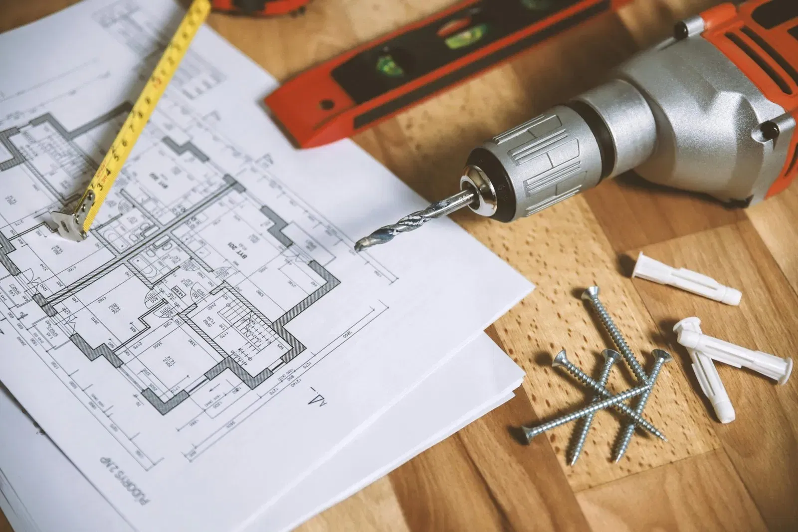 Tools and blueprints for home renovations, including a drill, screws, and a tape measure.