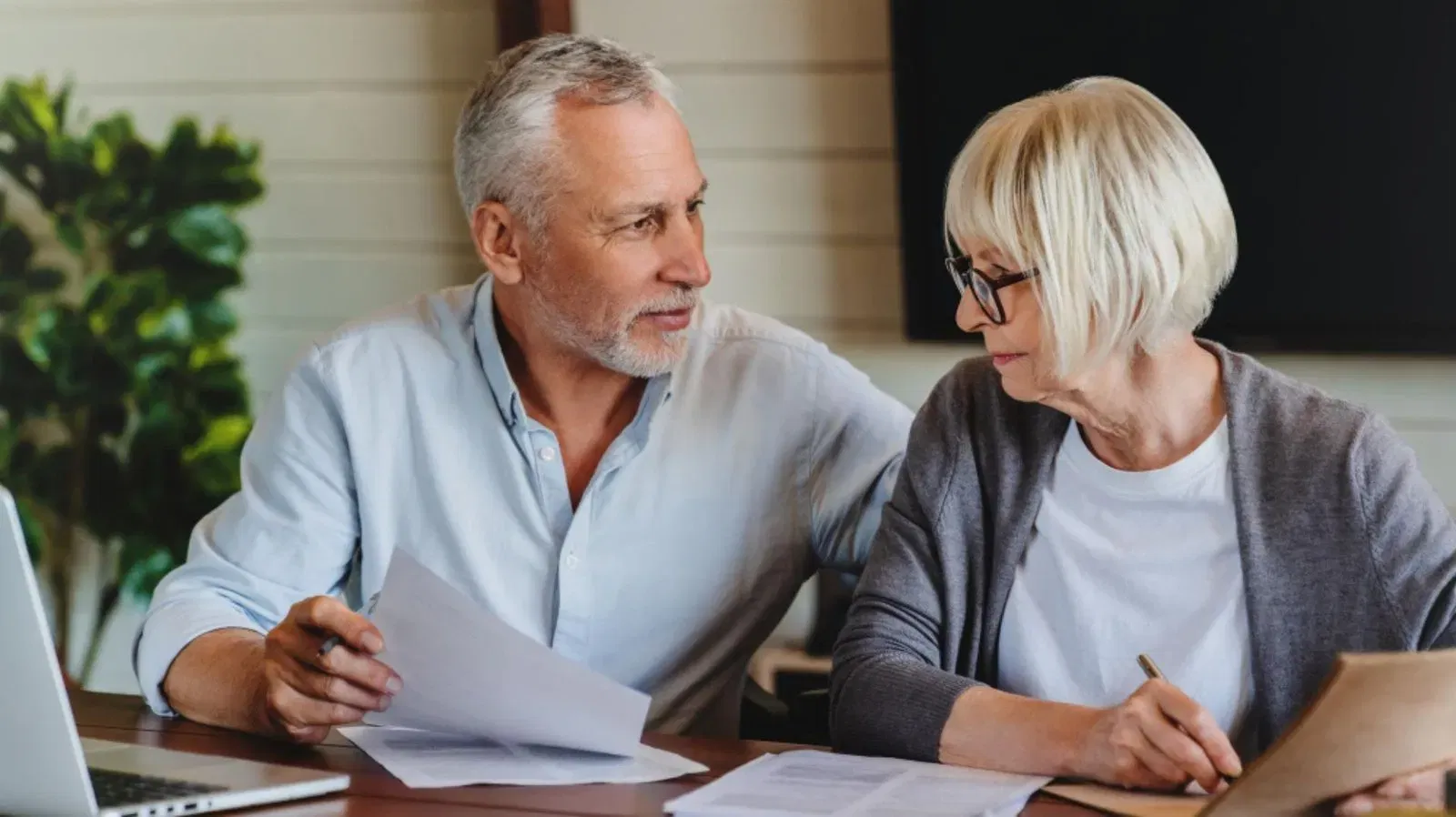 Senior couple reviewing financial documents, possibly related to wills and estates.