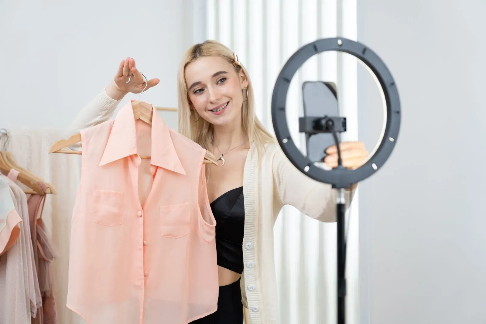 Influencer filming a fashion haul with a ring light, showcasing a peach blouse.
