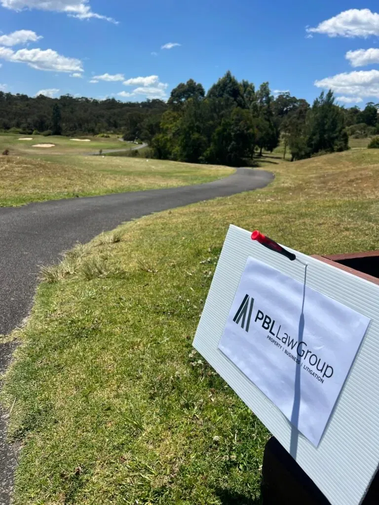PBL Law Group sign on a golf course, promoting their property, business, and litigation services.