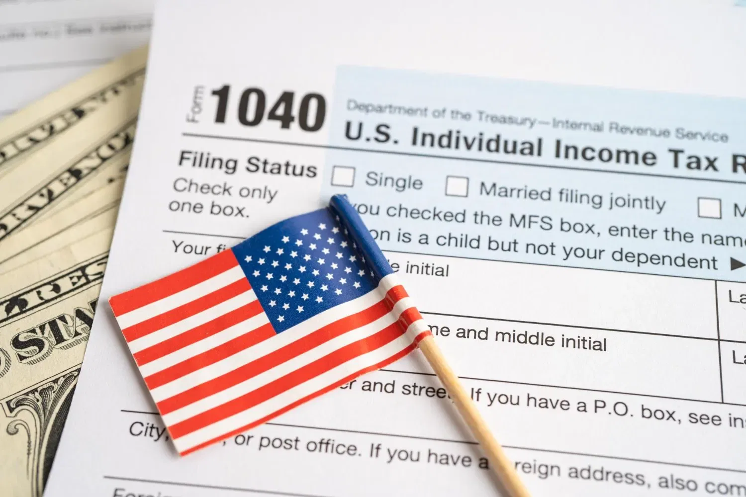 US 1040 tax form with American flag and cash. Filing taxes.