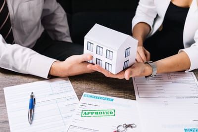 Mortgage application approved: People holding house model over loan papers. 