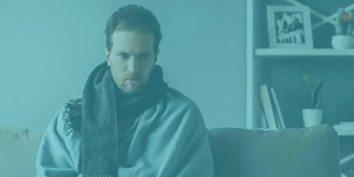 Worried man wrapped in a blanket, possibly ill.