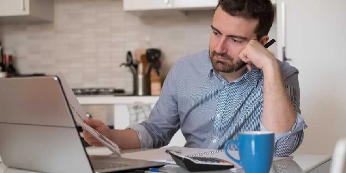 Concerned man reviewing finances on laptop, questioning pandemic's impact on liquidation business.