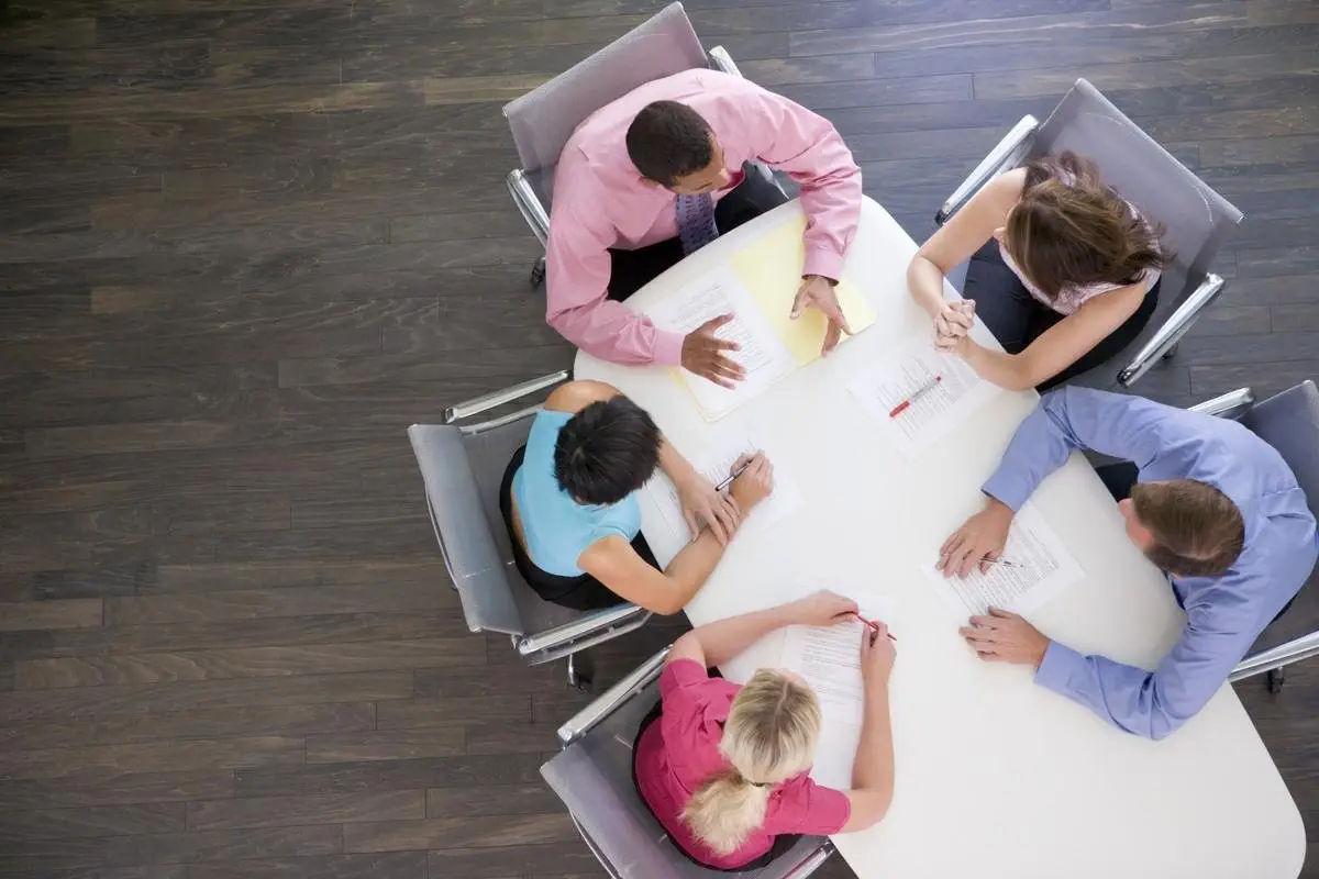 Four people sit around a table, collaborating on documents. Strata committee meeting.