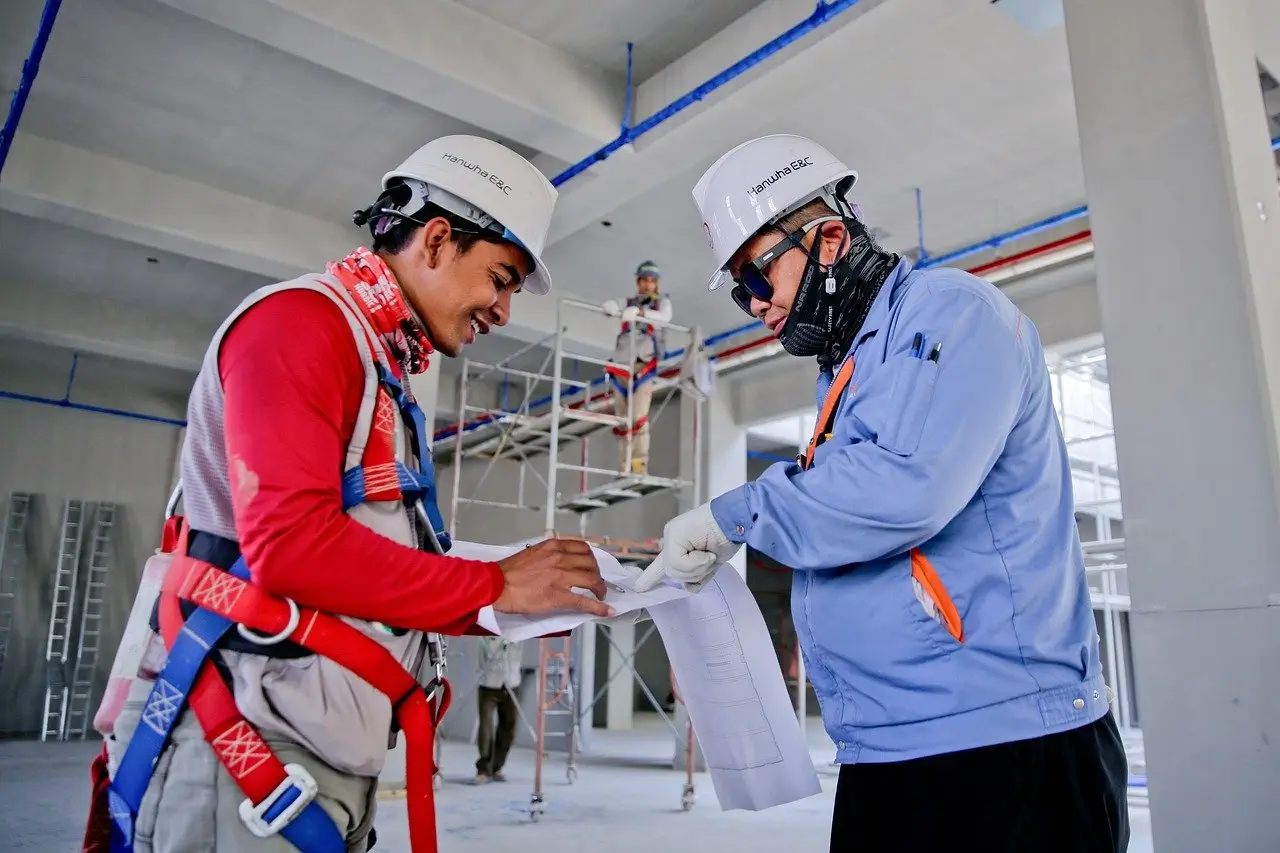 Construction workers reviewing blueprints on-site, related to Section 18B of the Home Building Act 1989 in NSW.