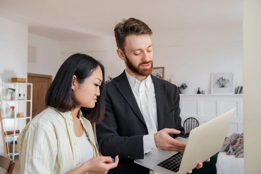 Financial advisor explaining international estate planning to client, laptop showing.