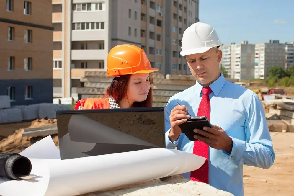 Construction professionals reviewing plans at a building site. Principal contractor obligations.