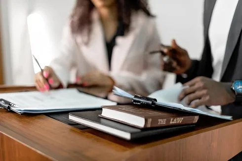 Two people reviewing legal documents with a law book, discussing contesting a will by estranged children in NSW.