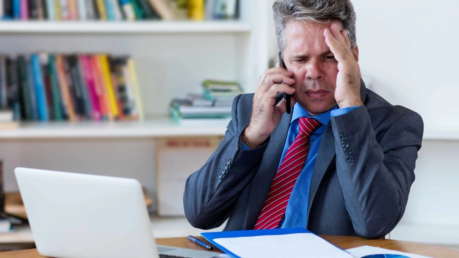 Stressed businessman on phone, concerned expression. Insolvency reform.