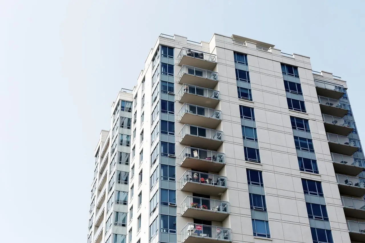 High-rise apartment building with multiple balconies and large windows under a clear sky.