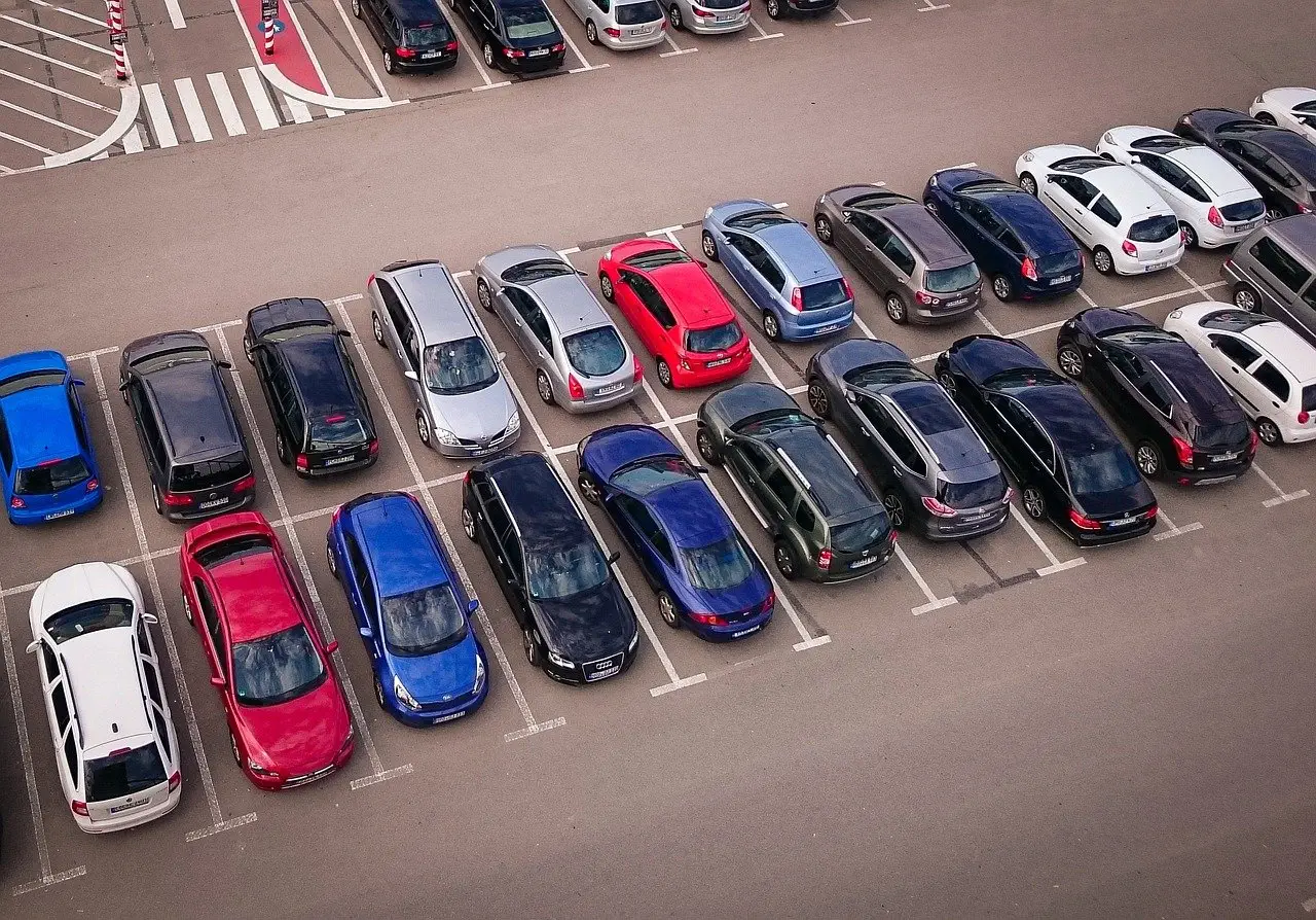 Aerial view of a parking lot filled with various colored cars arranged neatly in rows.